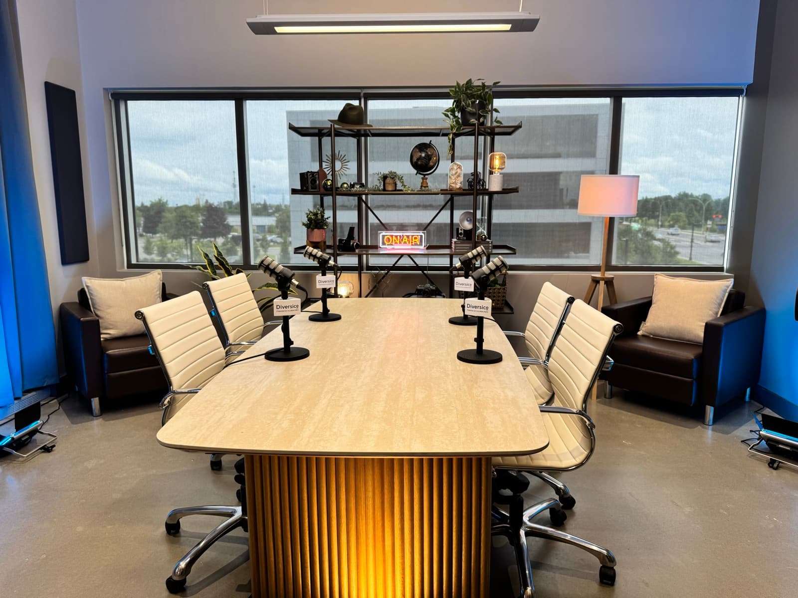 Le set corpo : grande table de bois clair, chaises et étagères devant les fenêtres