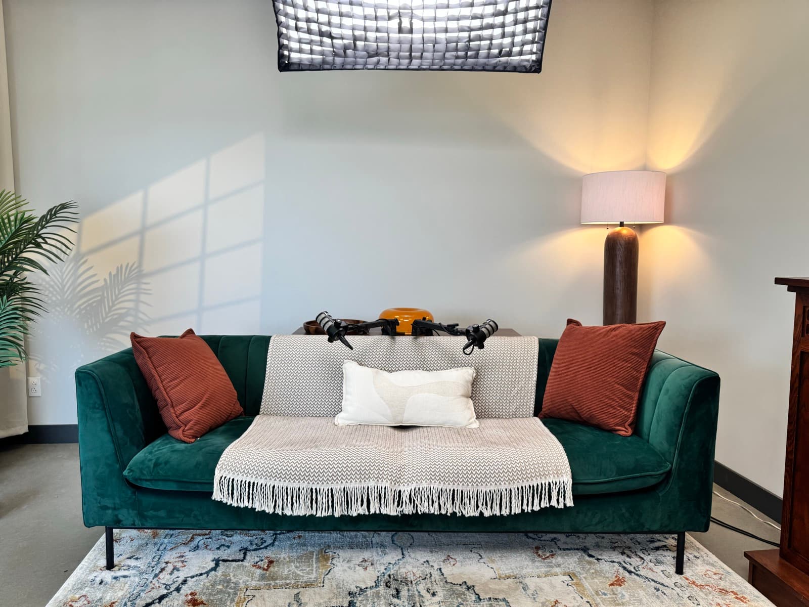 Sofa de velours vert avec coussins, éclairé par deux lampes